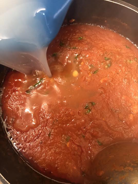 Pasta water being added to tomato