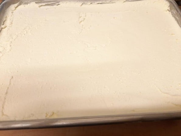 Cream spread over cake in tin