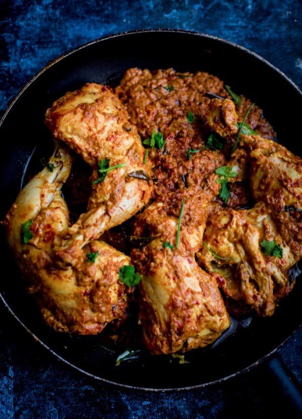 Chicken Ghee Roast in a black pan, topped with coriander