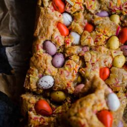 Mini Egg Blondies on baking paper with one piece cut out