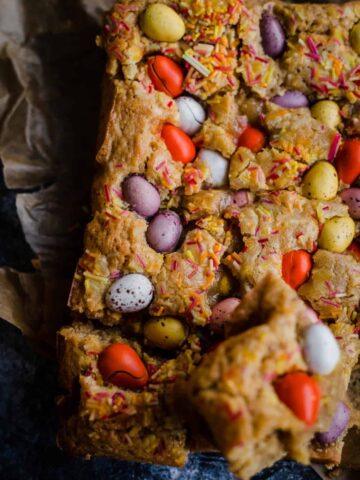 Mini Egg Blondies on baking paper with one piece cut out