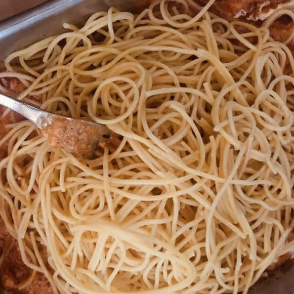 Spaghetti being mixed into tin