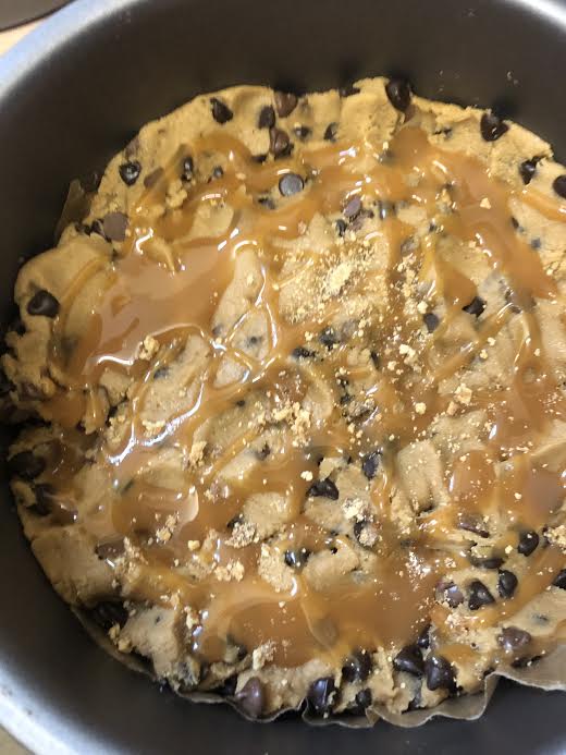 Caramel added to cookie dough layer in round tin