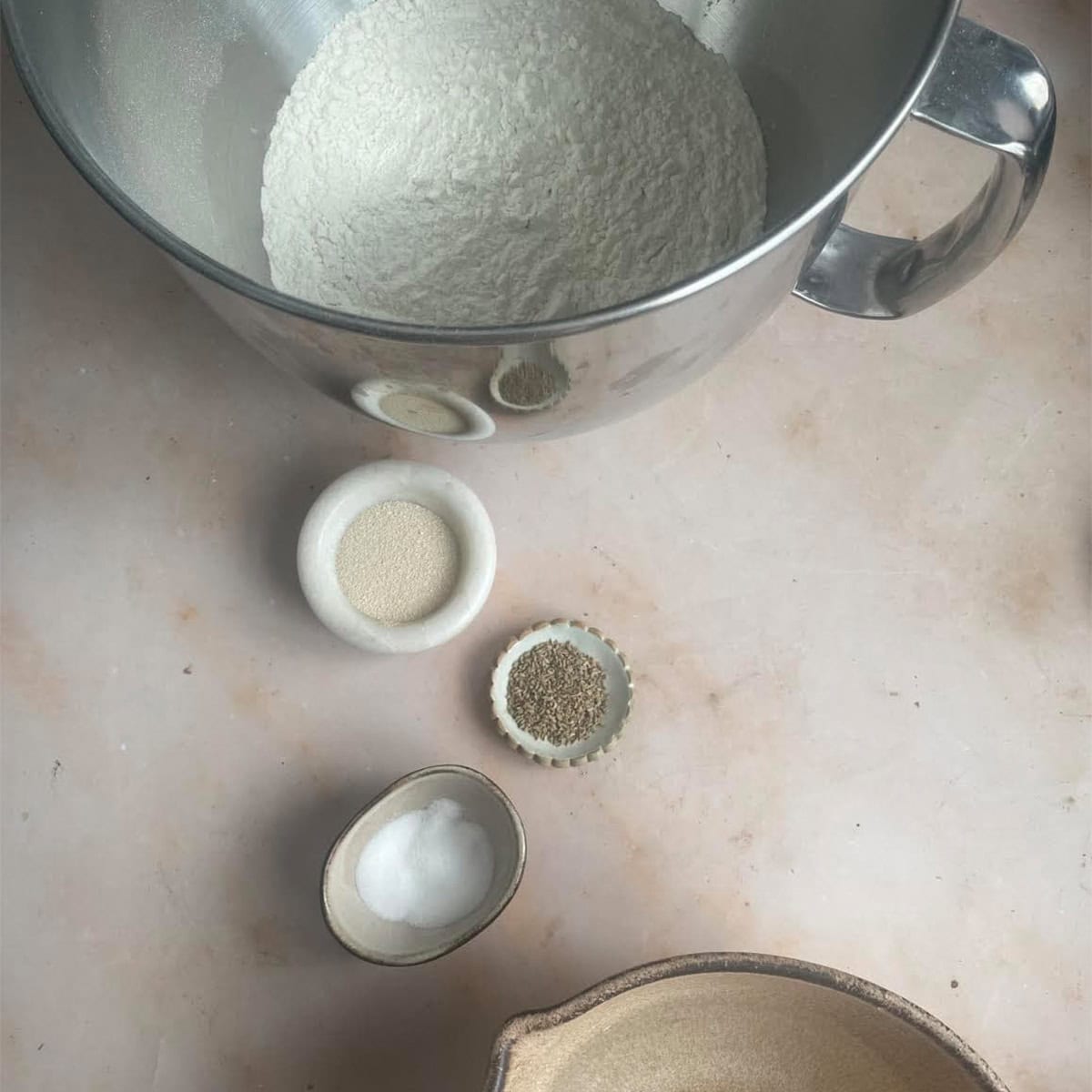 Flour, yeast, salt, and sugar in bowls for bread dough preparation.