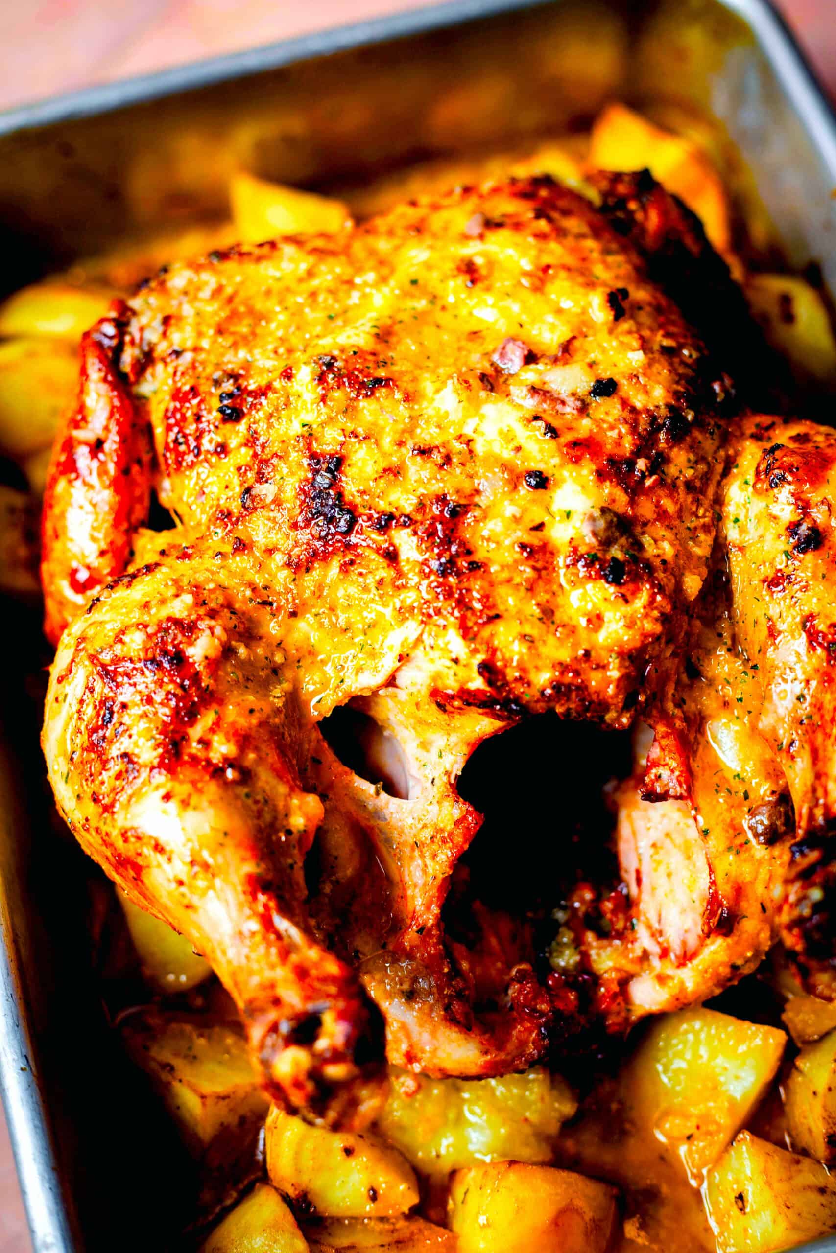 Greek Roast Chicken on a bed of potatoes in a tin