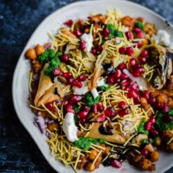 Samosa Chaat on a plate with pomegranate and sauces on top