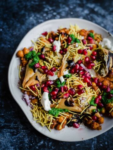 Samosa Chaat on a plate with pomegranate and sauces on top
