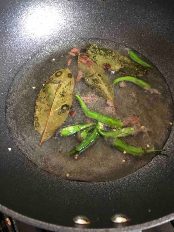 Oil with bay leave, chillies, cinnamon in wok