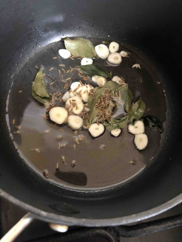 Oil with sliced garlic, curry leaves and cumin