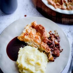 Lamb and sausage pie and mash in a plate with gravy