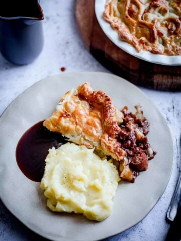 Lamb and sausage pie and mash in a plate with gravy