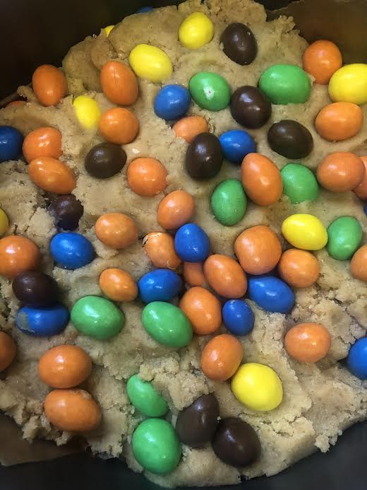 M&M added to cookie dough in cake tin