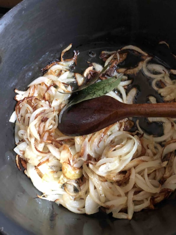 Whole spices added to golden onions in pot