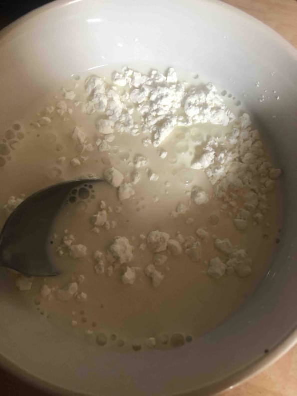 Cornflour and milk being whisked together in bowl