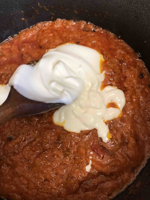 Yoghurt added to tomatoes in pot