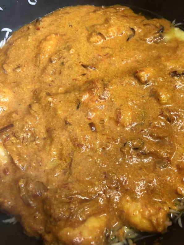 Prawn curry on top of rice layer in pot