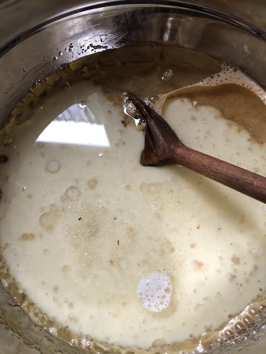 Milk and oil being stirred in bowl with wooden spoon 
