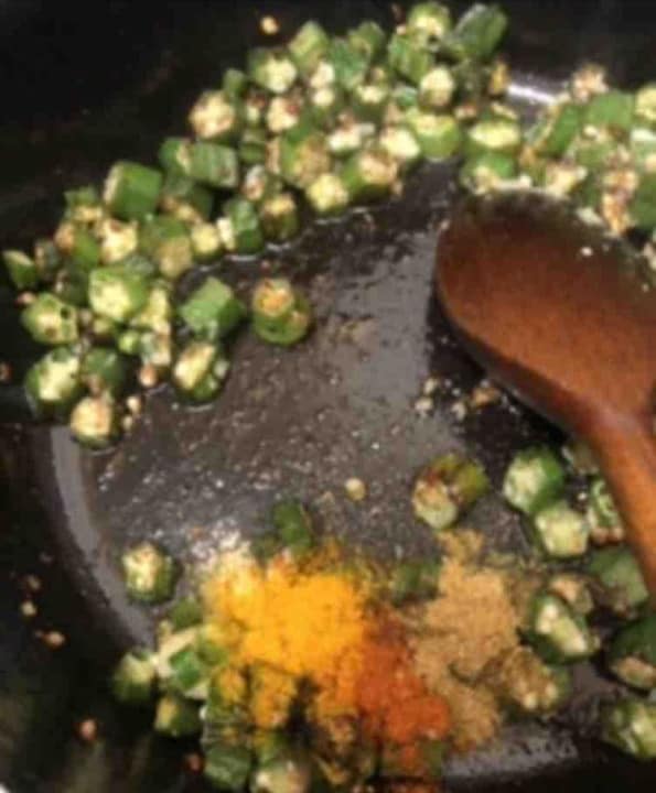 Ground spices added to pot with okra