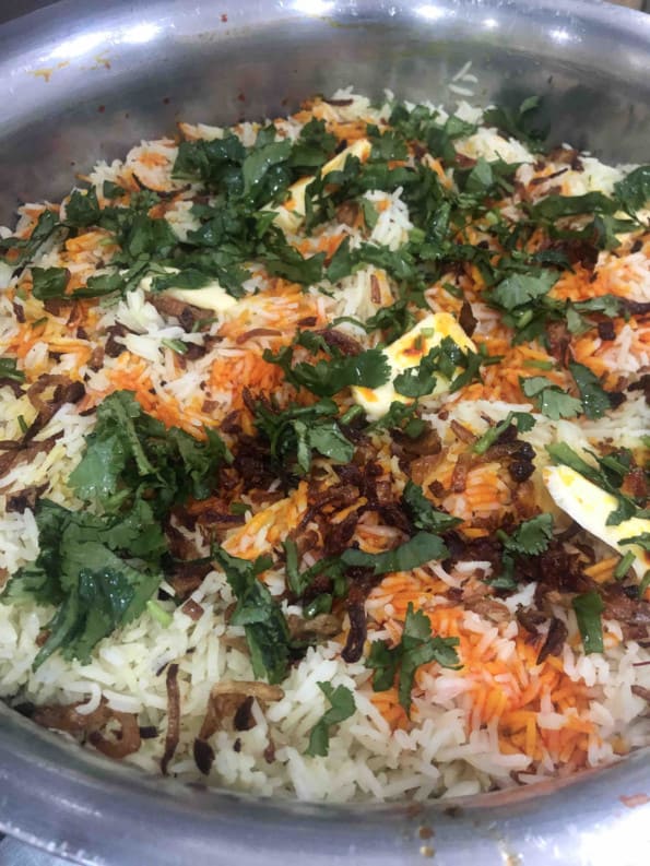 Biryani with coloured rice and coriander and fried onions on top
