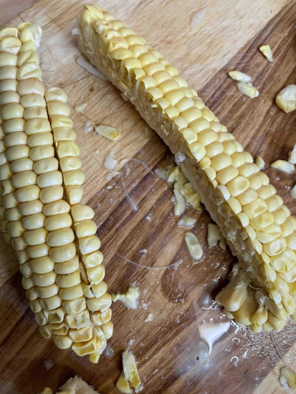 Corn cut into verticle quarters on chopping board