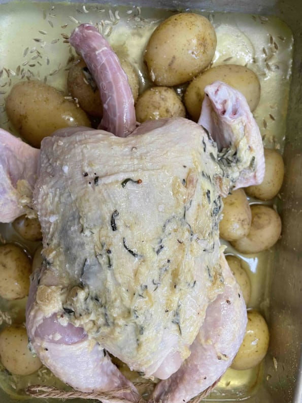Chicken on top of potatoes in tin
