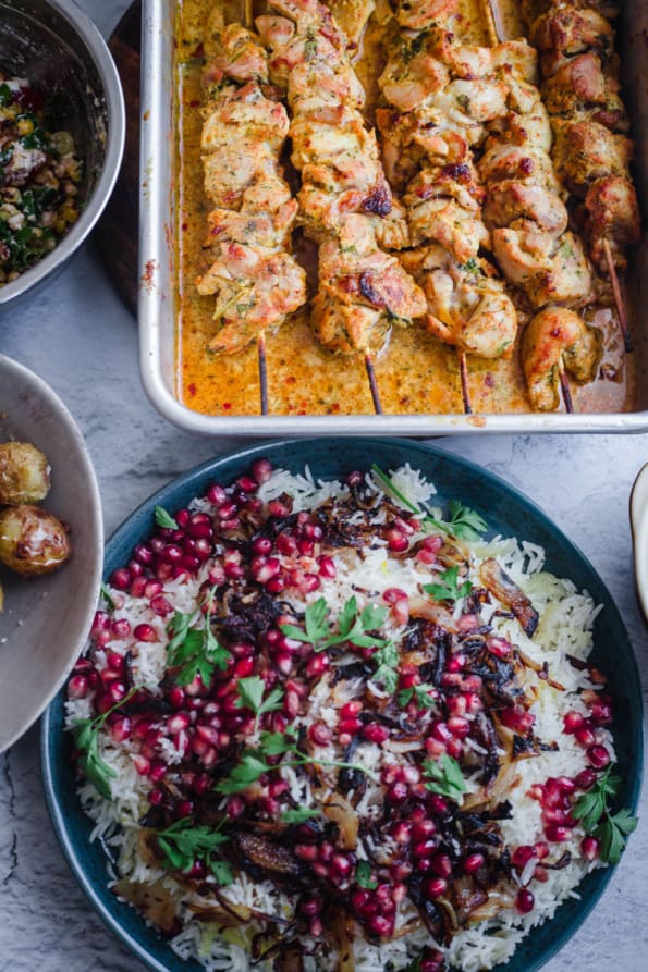 Jewelled rice with chicken skewers in tray to side