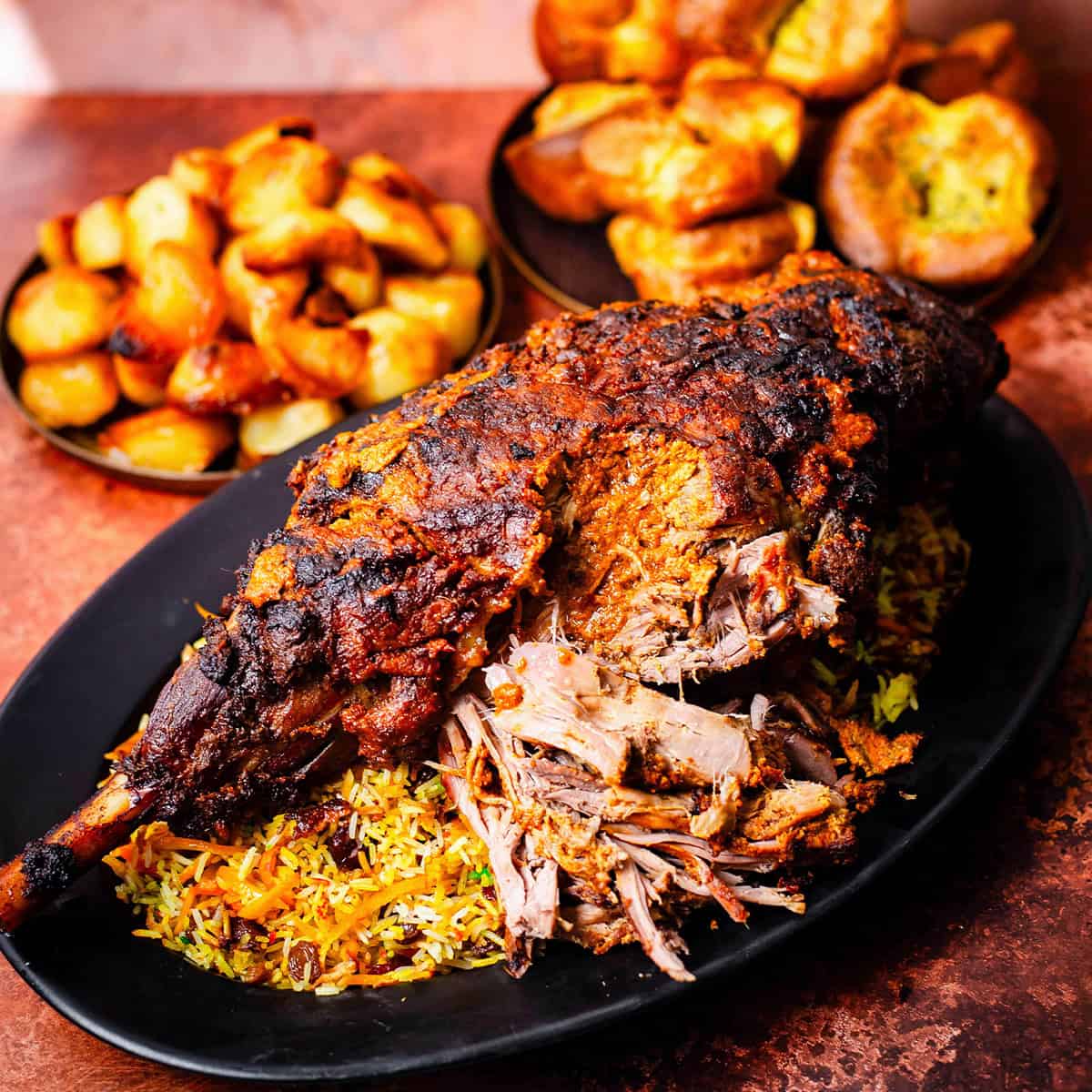 Lamb Leg with Rice on platter with roast potatoes and yorkshire puddings