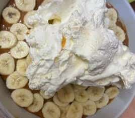 Cream added on top of bananas in dish