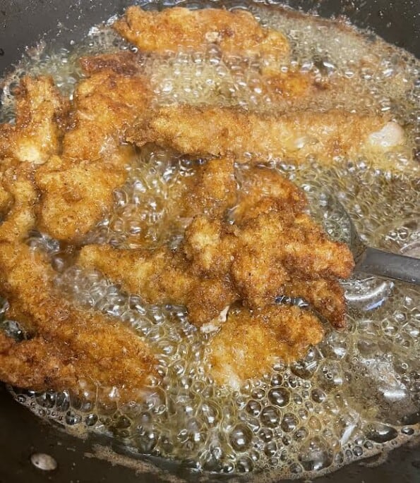 Chicken goujons frying in hot oil