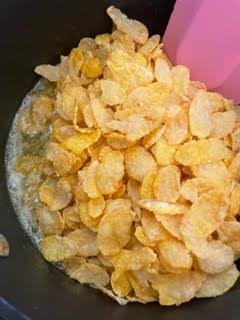 Cornflakes being stirred into syrup in pan