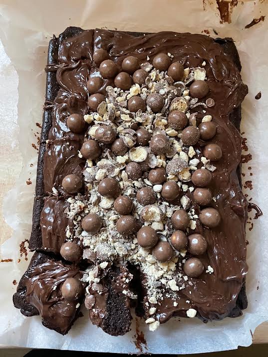Maltesers added to cake in tray