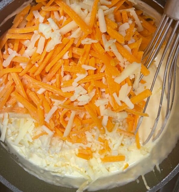 Grated cheese added to sauce in pot