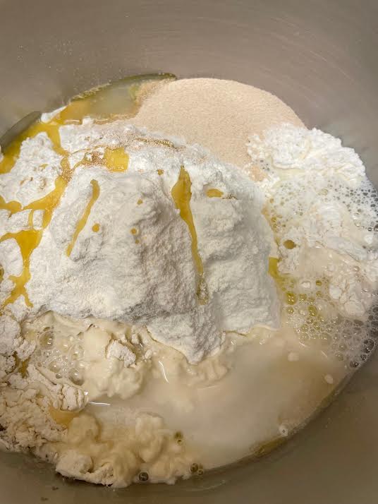 Water and Milk being added slowly to bowl of flour