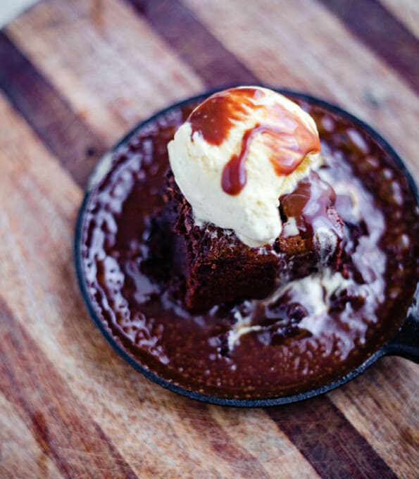Sizzling brownie dessert in a cast iron pan with ice cream on top