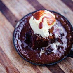Sizzling brownie dessert in a cast iron pan with ice cream on top