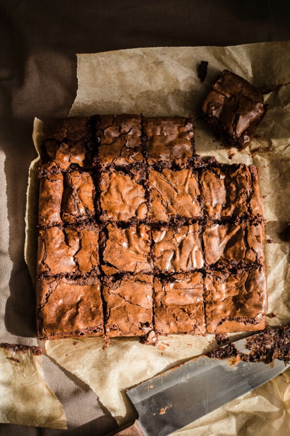 Baked brownies cut into 16 pieces on baking paper