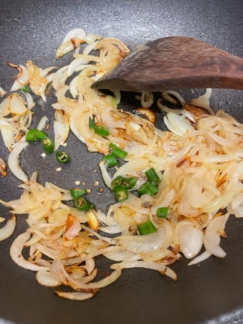 Green Chillies added to onions in wok