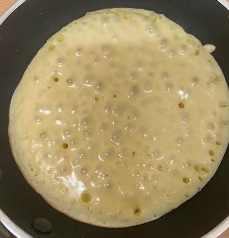 Pancake batter with bubbles on top in pan 