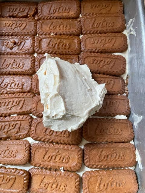 Cream being added on top of Biscoff biscuits in dish