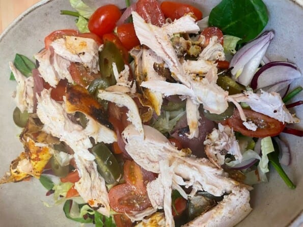 Chicken added on top of salad in bowl