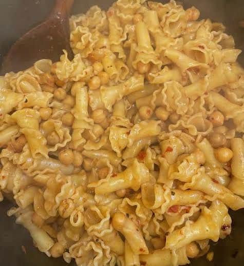 Pasta and chickpeas being stirred with wooden spoon 