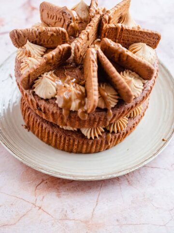 Biscoff cake with cream cheese frosting and biscuits on a plate