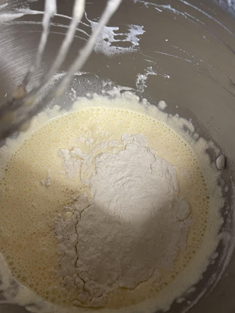 Flour mixture added to egg yolk mixture in bowl