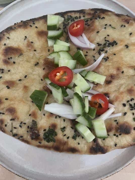 Salad added to Naan on plate