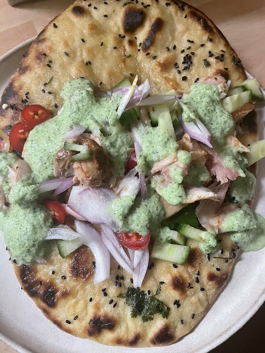 Chicken, salad and sauce added to Naan on plate