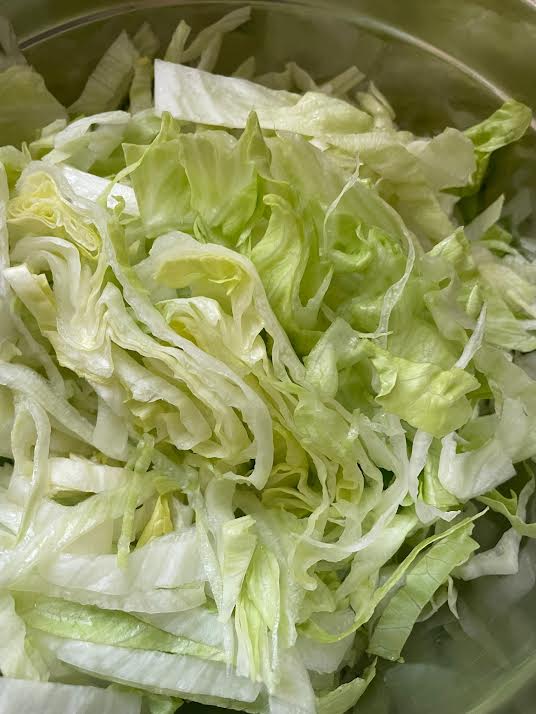Chopped romaine added to bowl