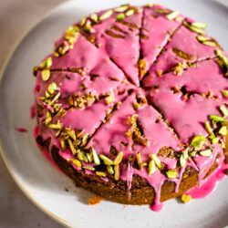 Raspberry Pistachio Cake cut into slices on a plate