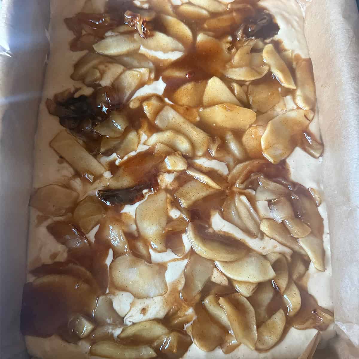 Cake batter and apple in tin