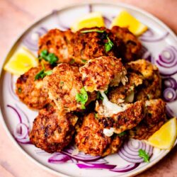 Chicken kebabs on a plate with lemon and onions