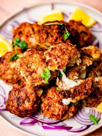 Chicken kebabs on a plate with lemon and onions